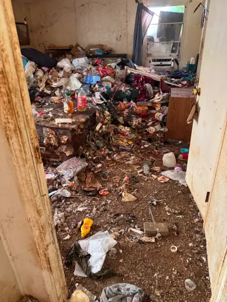 Floor buried in trash and debris before a hoarding cleanout