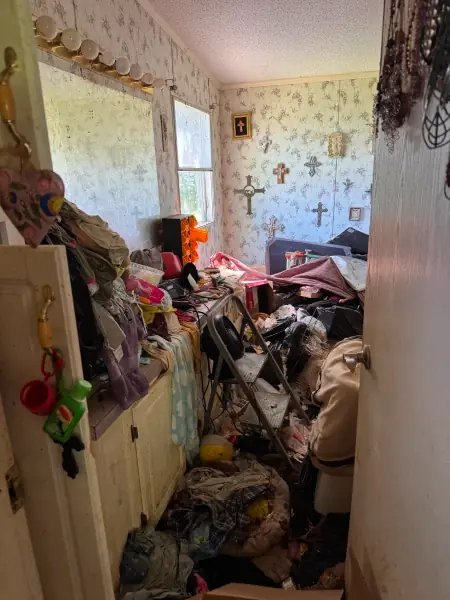 Cluttered bedroom piled with belongings before cleanup